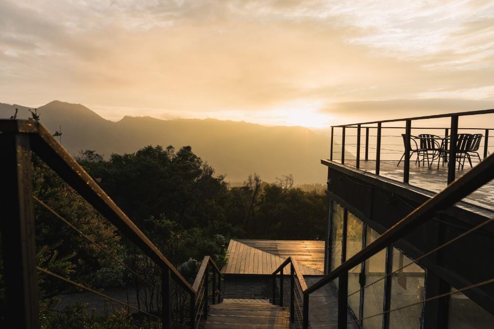 Sunrise view from Artotel restaurant in Cemaralawang Village, overlooking mountain silhouettes and a tranquil terrace