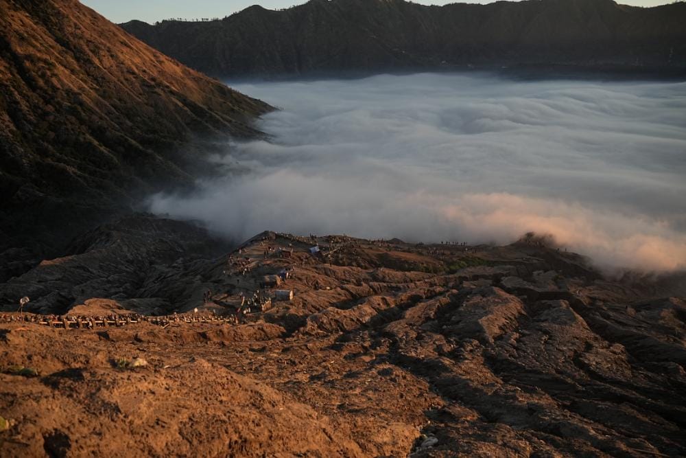 Scenic path leading to the summit of Mount Bromo with sunrise mist and volcanic fog in the background