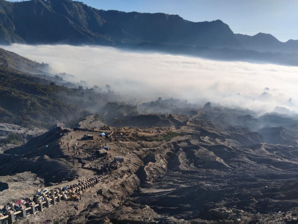 Panoramic view from Mount Bromo summit overlooking Pura Luhur Poten and the misty volcanic landscape.