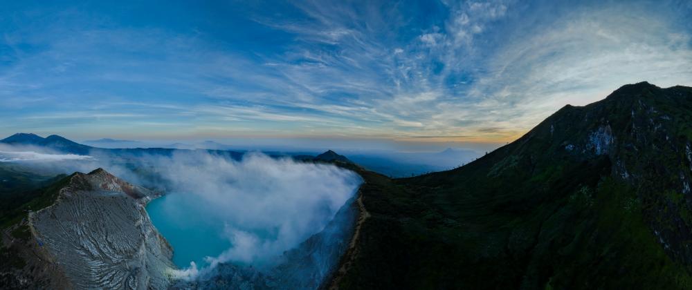 Panoramic view of Kawah Ijen with Moon Hill and the turquoise acid lake surrounded by volcanic slopes and clouds
