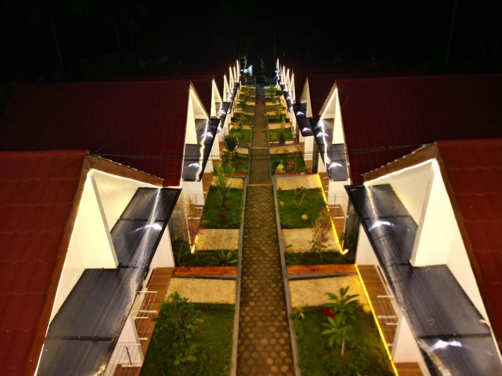 Nighttime aerial view of Sambas Cottage hotel courtyard with symmetrical rooftops and illuminated walkways