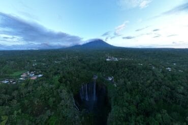 Drone view of Tumpak Sewu Waterfall with Mount Semeru in the background