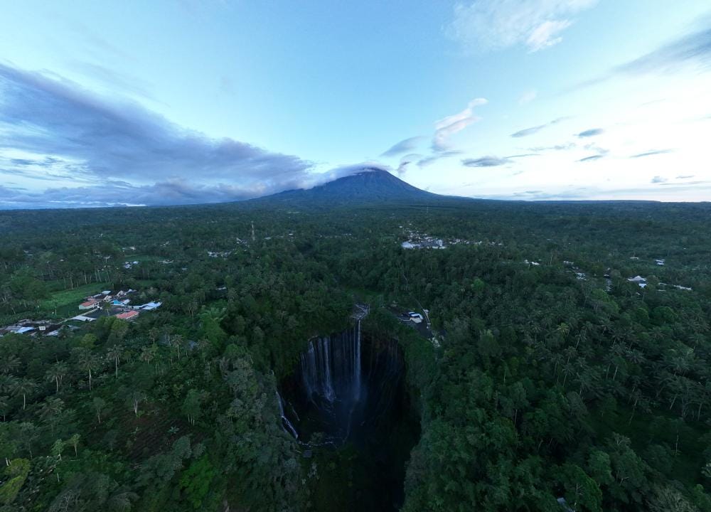 Drone view of Tumpak Sewu Waterfall with Mount Semeru in the background