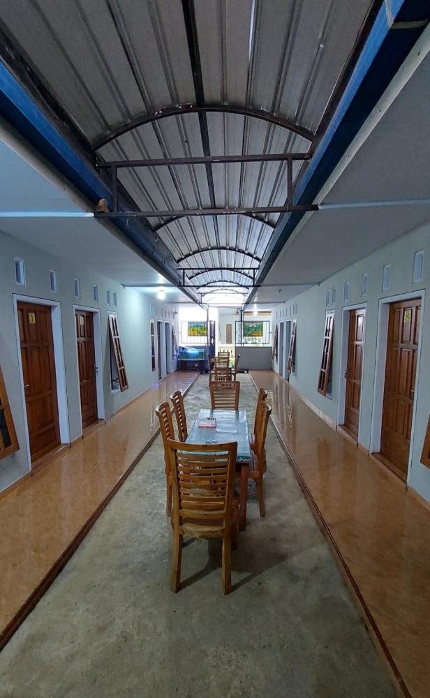 Standard room area at Yanto Homestay with a long covered corridor, wooden doors, and a simple dining table set in the center.